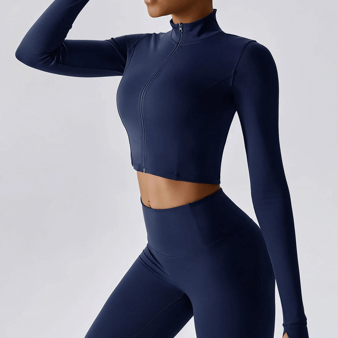 Woman wearing a navy blue long-sleeved fitness crop top with zipper, designed for quick-drying and comfort during high-intensity workouts.